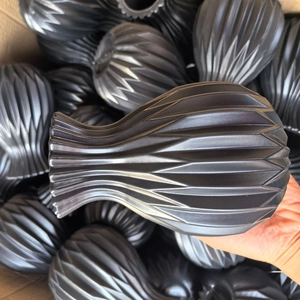 Macro detail of a black matte geometric vase with vertical textured origami patterns