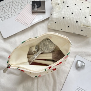 Flache Ansicht von floralen Kulturtaschen mit Pinseln und Spiegel neben einem Laptop