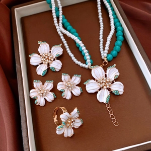 Detail view of vintage jewelry set with white floral enamel and turquoise beads