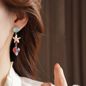 Detail of starfish dangle earring with blue glass bead on model for beach style fashion
