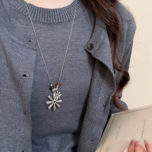 Detail of tiger eye bead and wrinkled flower pendant on a minimalist long silver necklace