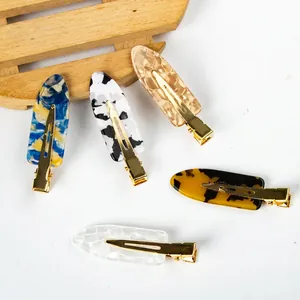Five assorted tortoiseshell pattern hair clips with gold metal base on white background