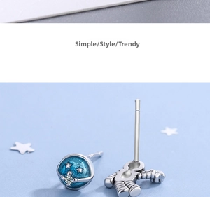 Detail view of asymmetric astronaut and blue planet stud earrings with silver stars