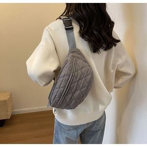 Rear view of a model wearing a grey quilted crossbody chest bag with adjustable strap