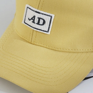 Detailed close-up of yellow cotton baseball cap with AD patch embroidery and stitching