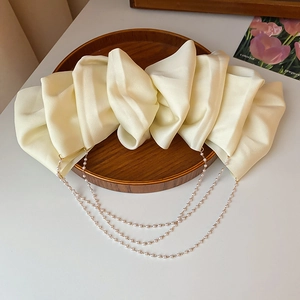 Detail of a large cream satin bow hair clip with layered faux pearl tassel chains