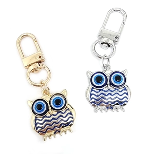 Detailed view of owl keychains with blue evil eyes in gold and silver metal finishes