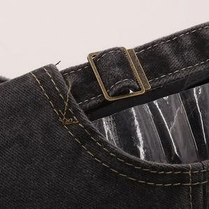 Macro shot of bronze metal slide buckle and yellow stitching on grey denim cap