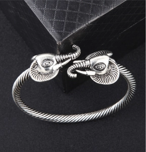 Close-up of vintage twisted metal cuff bracelet featuring dual elephant head details