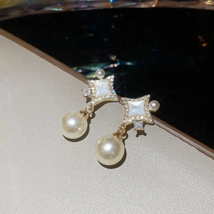 Gros plan détaillé des boucles d'oreilles étoile dorées avec zircon et perles rondes