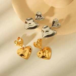 Hammered heart drop earrings in gold and silver finish on ceramic display