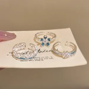 Three-piece set of silver flower rings with sky blue enamel details and twisted bands