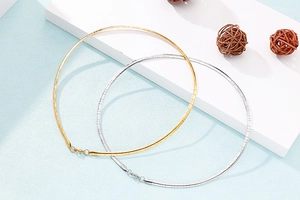 Detailed view of polished gold and silver metal collar necklaces on display stands