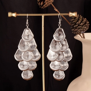 Detail of silver layered shell tassel earrings hanging on a display rack with elegant background