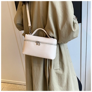 Detailed view of white litchi pattern leather box bag with dual zippers and shoulder strap