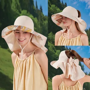 Beige wide brim sun hat with neck flap and bow tie, leaf print lining outdoors