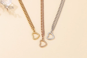 Detail of layered titanium steel necklaces with heart pendants in gold, silver, and rose gold