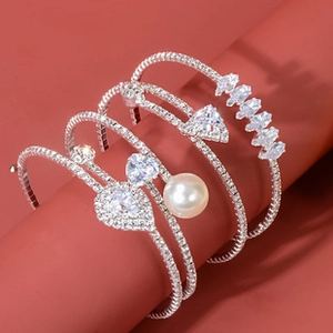 Detail of silver drop bracelets with crystals and pearls on a red backdrop