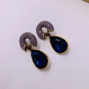 Detailed macro view of vintage baroque teardrop earrings with blue stone and purple crystals