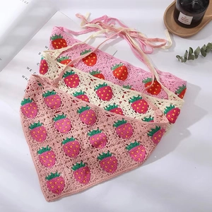 Close-up of three handmade crochet strawberry bandanas in pink, beige, and rose pink