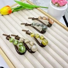 Detailed close-up of colorful cat-eye stone hair clips on a textured jewelry stand