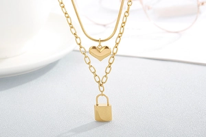 Close-up of golden double-layer necklace with heart and lock pendants on desktop