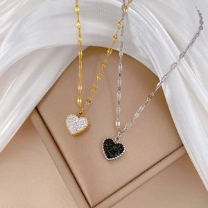 Detailed close-up of gold and silver titanium steel heart necklaces on beige box