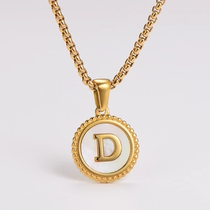 Detailed close-up of a gold-plated necklace featuring a round pendant with a white shell 'D' letter
