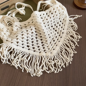 Detail view of cream crochet triangle scarf featuring openwork patterns and long tassels