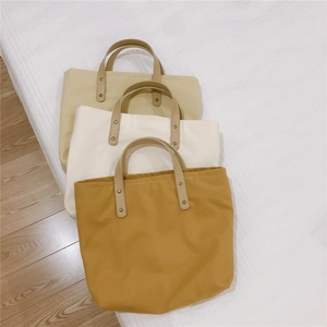 Three minimalist canvas tote bags in ginger, cream, and beige colors with leather handles