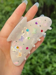 Dettaglio della pinza per capelli a farfalla bianco perlato con strass colorati e decori
