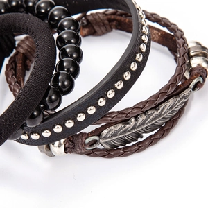 Close-up of multilayer leather bracelets set with silver feather charm and vintage studs