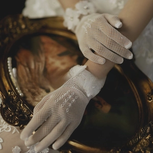 Detail of vintage white lace bridal gloves with 3D floral pearls on mesh fabric