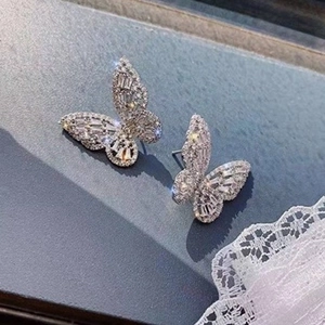 Close-up of butterfly stud earrings with sparkling cubic zirconia on a dark grey surface