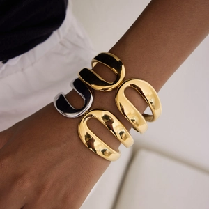 Detail of high-polish U-shaped 18k gold and silver spring bangles on wrist