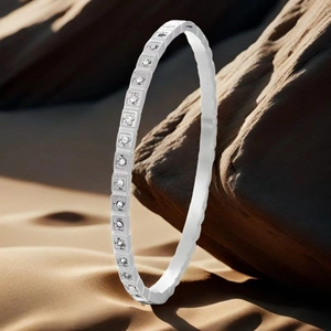 Detail of silver S925 stamped bangle with square set zircons on a textured rock