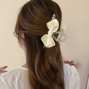 Elegant cream bow hair claw with rhinestones shown on a model from the back view