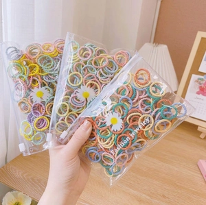 Hand holding 3 packs of high elasticity colorful hair ties, 100 pieces per bag