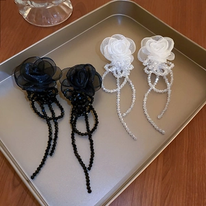 Vue détaillée de boucles d'oreilles fleurs en organza noir et blanc avec glands