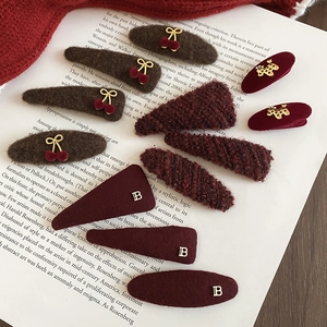 Detailed view of plush velvet triangular and oval hair clips in dark brown and wine red