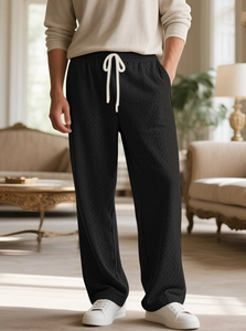 Detail view of men's black waffle knit texture and drawstring waist on casual pants