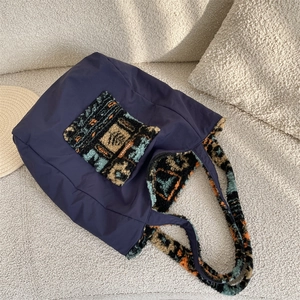 Detail of navy nylon tote bag showing vintage fleece pocket and leather label