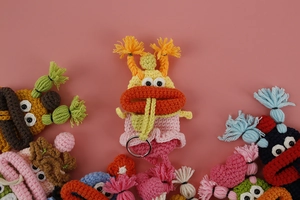 Close-up of handmade knitted monster key covers in various colors with metallic rings