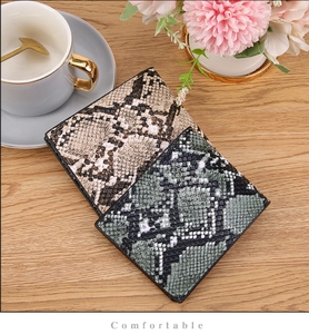 Detailed view of snake skin texture wallets on a desk with elegant lifestyle accessories
