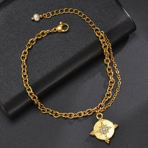 Detail of gold double-layer chain bracelet with star coin pendant and small white pearl