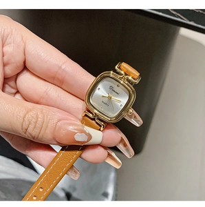Elegant gold square quartz watch with brown leather strap worn on woman's wrist
