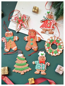 Flat lay of gingerbread man clay ornaments with Christmas tree decor and red ribbons