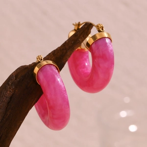 Nahaufnahme der rosa Harz-Ohrringe mit Goldakzenten an Vintage-Holz für Damen