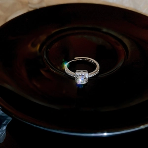Macro shot of silver adjustable square zircon ring with pave setting on dark glossy surface