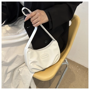 White crescent underarm bag with matte leather texture shown on model in stylish setting